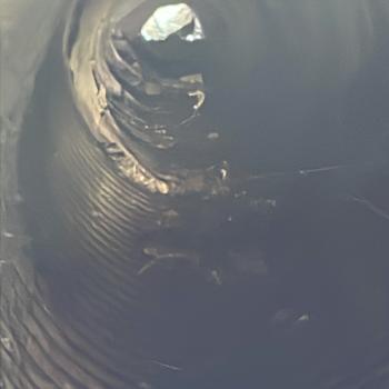 Photo shows the interior of a corrugated steel culvert with visible despiralling, where the corrugation has separated and twisted along the upper section.