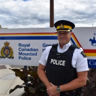 RCMP Officer In Charge Blake MacLeod in front of the sign
